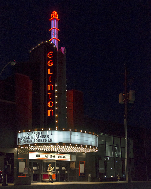 A night shot of an old movie theatre with its marquee lights